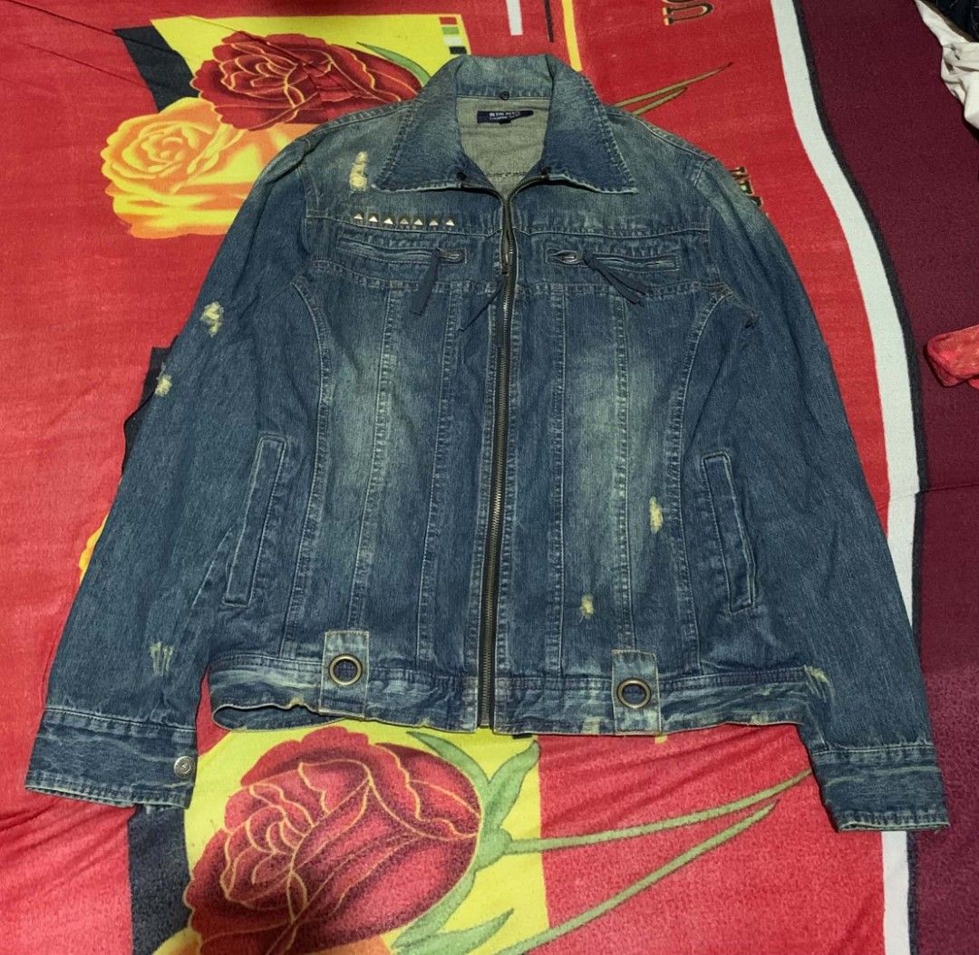IN THE ATTIC DISTRESSED ZIP-UP DENIM JACKET (Category: Coats, Jackets and Outerwear) located in Davao. Submitted by thrift_cuttiiee1000 (Listing ID 1461712221, Image 2). Description: Design & Features: Distressed Aesthetic: Heavily faded, worn-in blue denim with shredded (distressed) details throughout . Utility & Punk Hardware: Metal pyramid studs above the chest, zippers, decorative pull-ties, and distinctive oversized metallic grommets/eyelets