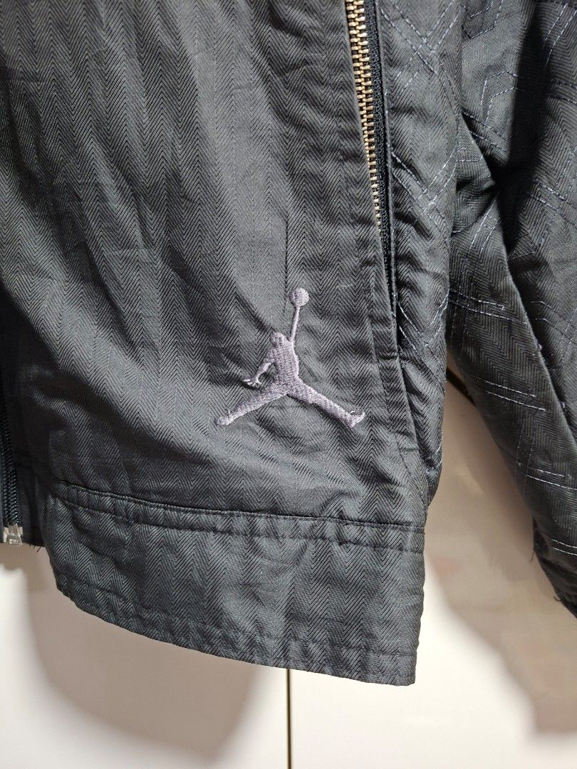 Jordan Bomber Jacket Black Size L (Category: Coats, Jackets and Outerwear) located in Cebu City. Submitted by anton_delos_reyes (Listing ID 1461624820, Image 3). Description: - Black Jordan bomber jacket - Size: Large (L) - Origin: Made in Thailand - Closure: Zip-up front - Pockets: Multiple zip pockets - Details: Ribbed collar, cuffs, and hem - Design: Subtle fabric pattern - Branding: Embroidered Jumpman logo on chest.