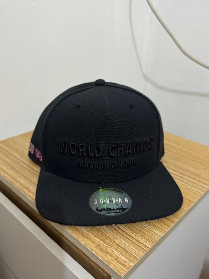 Jordan World Champions Again and Again Snapback Cap (Category: Caps & Hats) located in Bulacan. Submitted by alshopie (Listing ID 1461635715, Image 1). Description: - Black Jordan snapback cap - Embroidered 'WORLD CHAMPS AGAIN AND AGAIN' on the front - Embroidered '91 92 93' on the side - Original Jordan logo sticker still on the brim - Ideal for any Michael Jordan enthusiast.