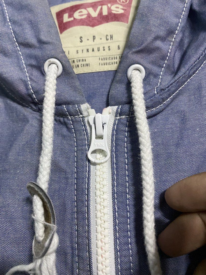 Levi's Lightweight hoodie zip up (Category: Hoodies) located in Manila. Submitted by callejage69430 (Listing ID 1461736115, Image 2). Description: 22 width 27 Length Issue discoloration This is a Levi's blue hooded zip-up windbreaker or lightweight jacket with white drawstrings and zipper accents..
