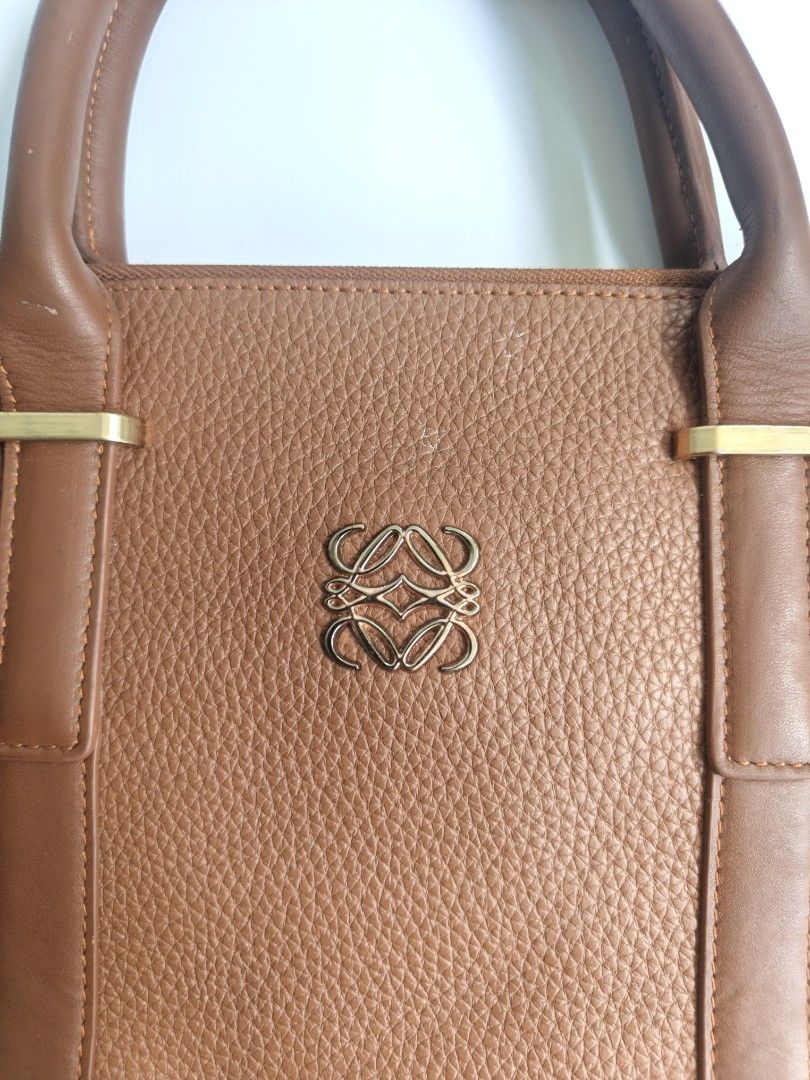 Loewe Postal Brown Leather Handbag with Shoulder Strap (Category: Luxury Bags & Wallets) located in Cavite. Submitted by benta_bounce (Listing ID 1461618710, Image 3). Description: - Stylish brown pebbled leather tote bag - Elegant gold hardware details - Comfortable top handles - Includes a detachable shoulder strap for versatility - Secure zipper closure to keep your belongings safe - Multiple interior compartments for organized storage - Spaci