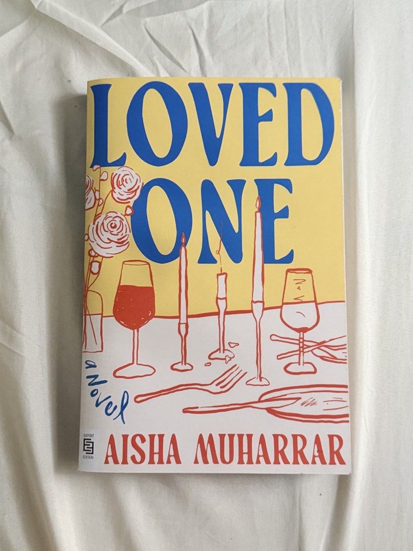 Loved One Novel by Aisha Muharrar (Category: Storybooks) located in Manila. Submitted by granddeer.488070 (Listing ID 1461586973, Image 1). Description: - Loved One novel by Aisha Muharrar - Features a yellow cover with blue text - Design includes roses, wine glasses, and candles - Export Edition - A great read for novel enthusiasts MOP: Maribank, BPI MOD: JNT Direct.