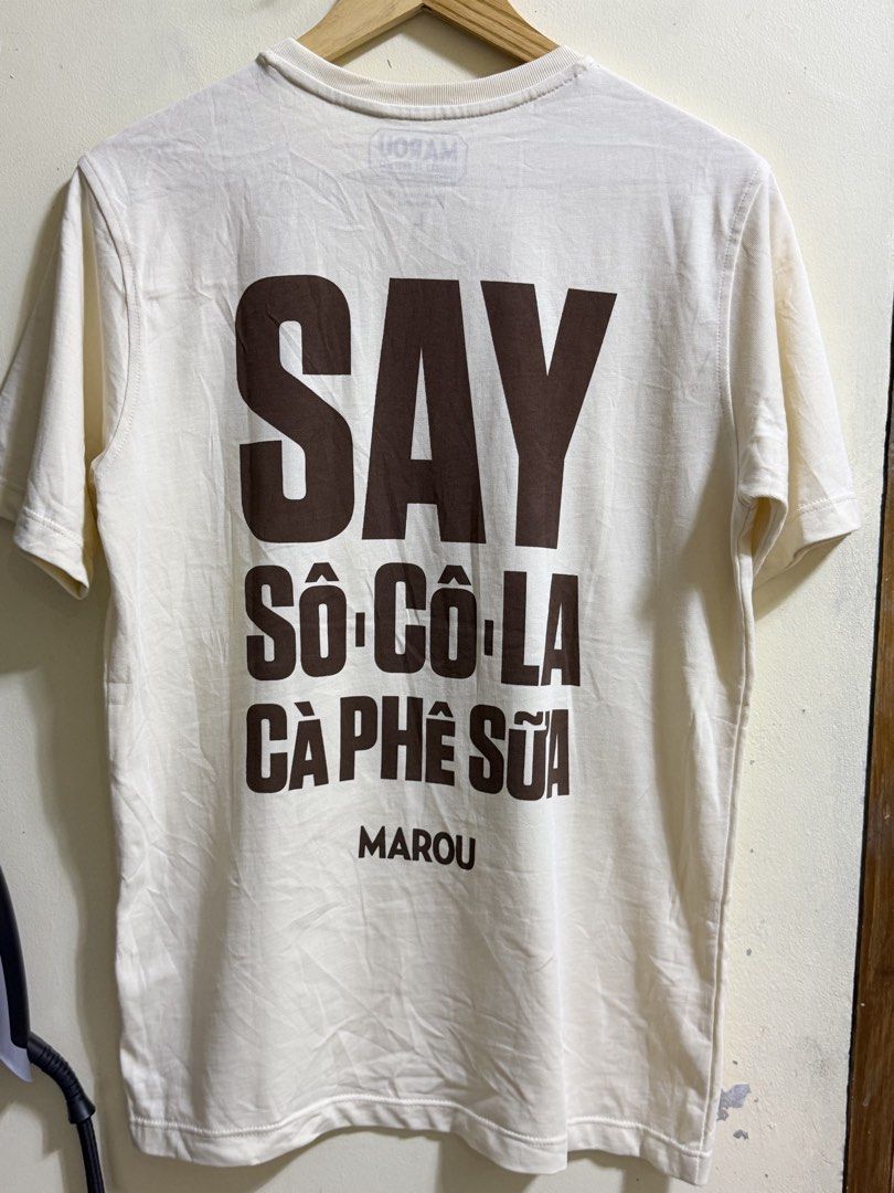 MAROU FAISEURS DE CHOCOLAT Signature Tee (Category: Shirts) located in Paete. Submitted by skydruemadison (Listing ID 1461761580, Image 3). Description: - Cream colored Marou t-shirt - Size L - Short sleeves - Chest pocket with brown 'M' logo - Large brown text on back: 'SAY SO CO LA CA PHE SUA MAROU' - Crafted in Vietnam.