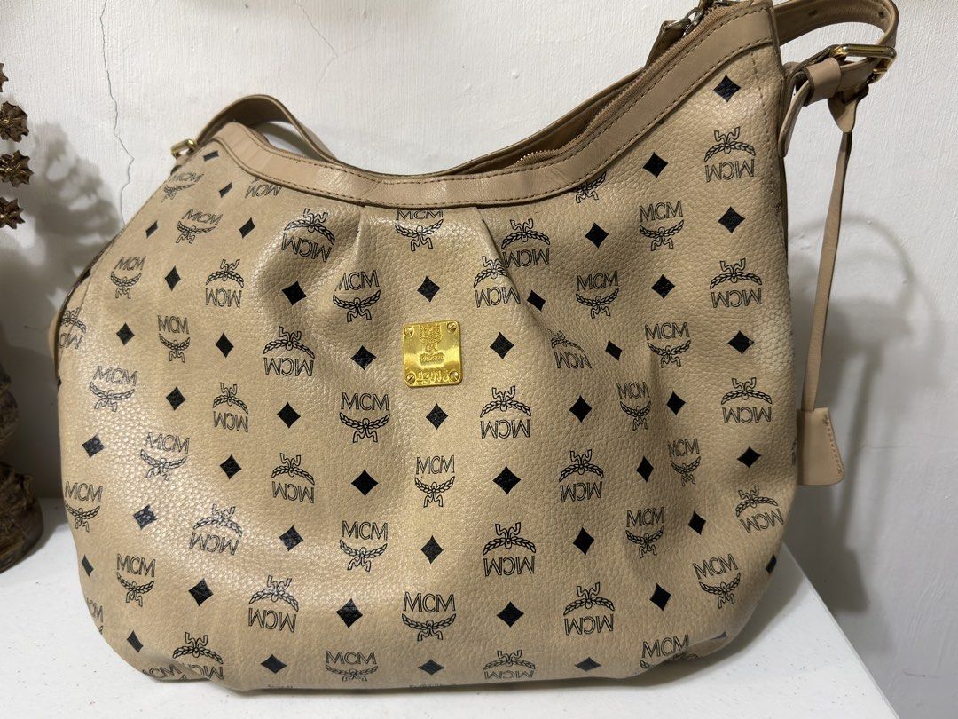 MCM Monogram Hobo Bag (Category: Luxury Bags & Wallets) located in Tarlac. Submitted by jzennoroyy-32960 (Listing ID 1461598974, Image 1). Description: - Authentic MCM hobo bag - Classic monogram print - Beige and black colorway - Gold hardware details - Zipper closure - Comes with padlock - Ideal for everyday use.