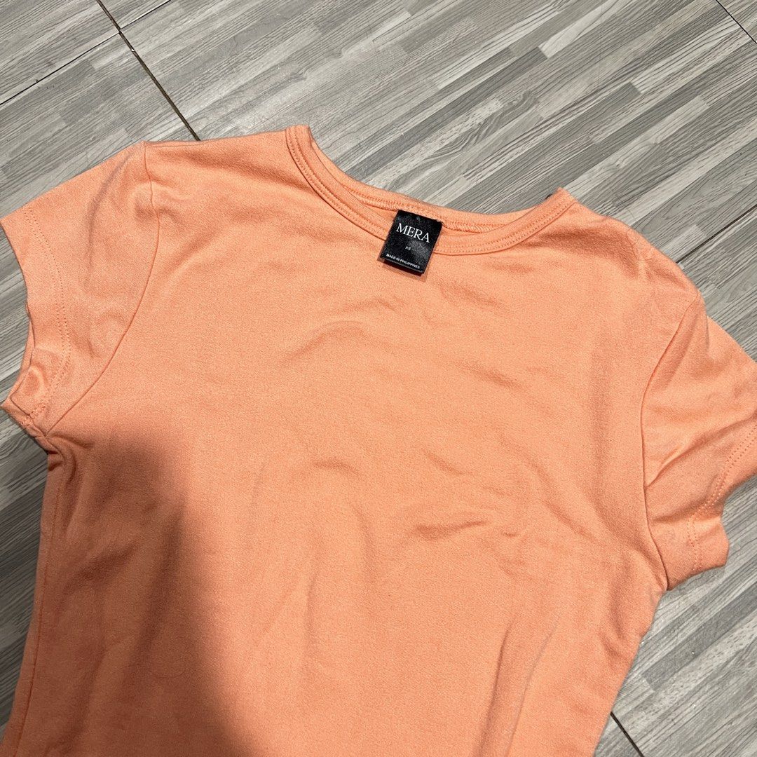 Mera Shirt & White Tank Top Bundle (Category: Shirts) located in Las Pinas. Submitted by veamesia_ (Listing ID 1461564301, Image 2). Description: - Bundle includes: 1 peach short-sleeved t-shirt (Mera) and 1 white sleeveless tank top. - Ideal for everyday wear, casual outings, or layering. ‼️Used once/Preloved ‼️ XS on tag .