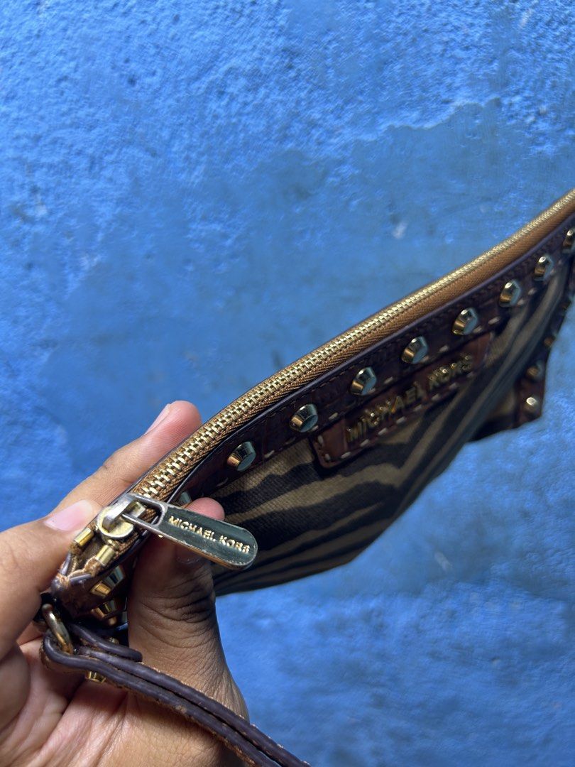 Michael Kors Zebra Print Clutch with Studs (Category: Clutches) located in Quezon City. Submitted by thriftxgoods (Listing ID 1461658287, Image 3). Description: - Stylish Michael Kors clutch - Eye-catching zebra print - Genuine brown leather trim - Elegant gold stud detailing - Secure zipper closure - Convenient interior pocket - Detachable wrist strap for easy carrying - Ideal for holding your essentials.