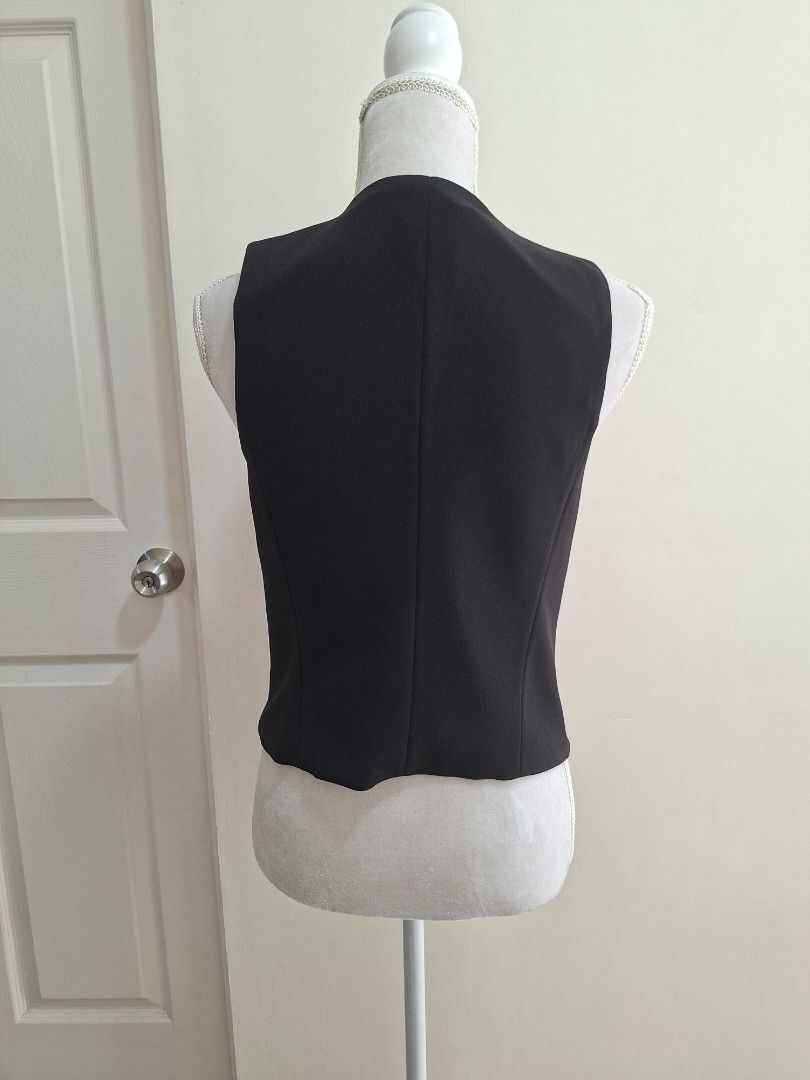 MNG Black Sleeveless Vest Size M (Category: Sleeveless) located in Pasig City. Submitted by avcan (Listing ID 1461576796, Image 3). Description: - MNG black sleeveless vest - Button-up front with 3 buttons - Made in Vietnam - Ideal for layering over shirts or dresses - Versatile for smart casual or formal looks - Please check photos for condition details - Note that one button at the bottom is not attached, but I pinned it to the washtag (DIY sew