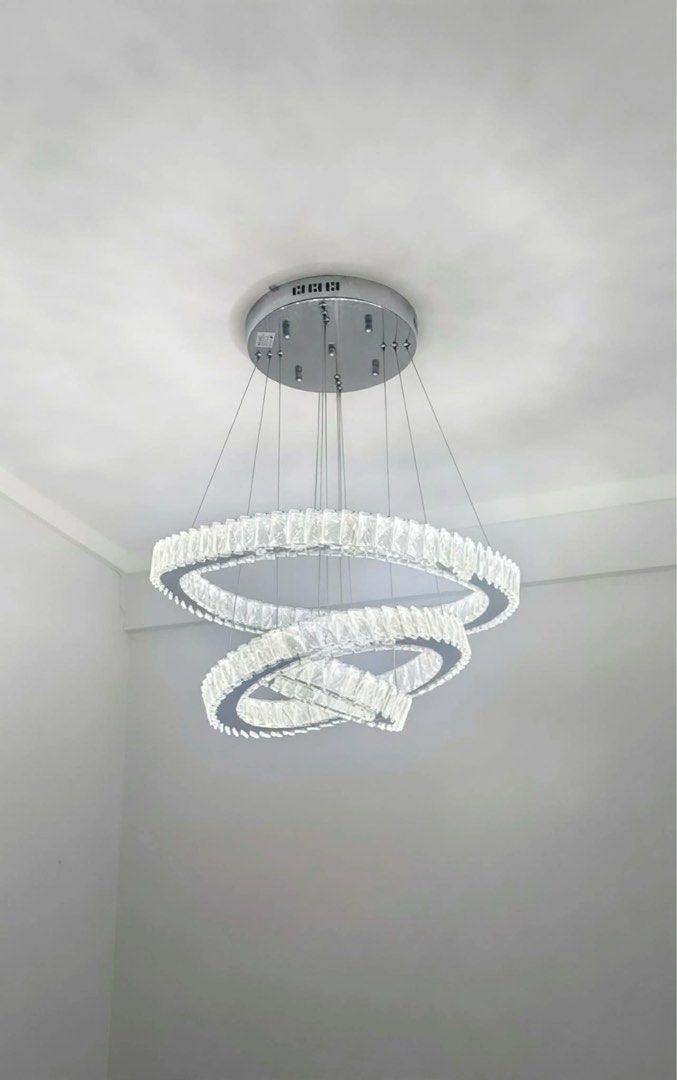 Modern Crystal Ring Chandelier Light Fixture (Category: Lighting) located in Manila. Submitted by d_carthub (Listing ID 1461590410, Image 1). Description: - Beautiful modern chandelier - Features three intertwined crystal rings - Silver-toned metal base - Emits bright, clear light, warm light - Ideal for living rooms, dining areas, or entryways - Adds a touch of sparkle - Wiring and mounting hardware included - 3 way light color.