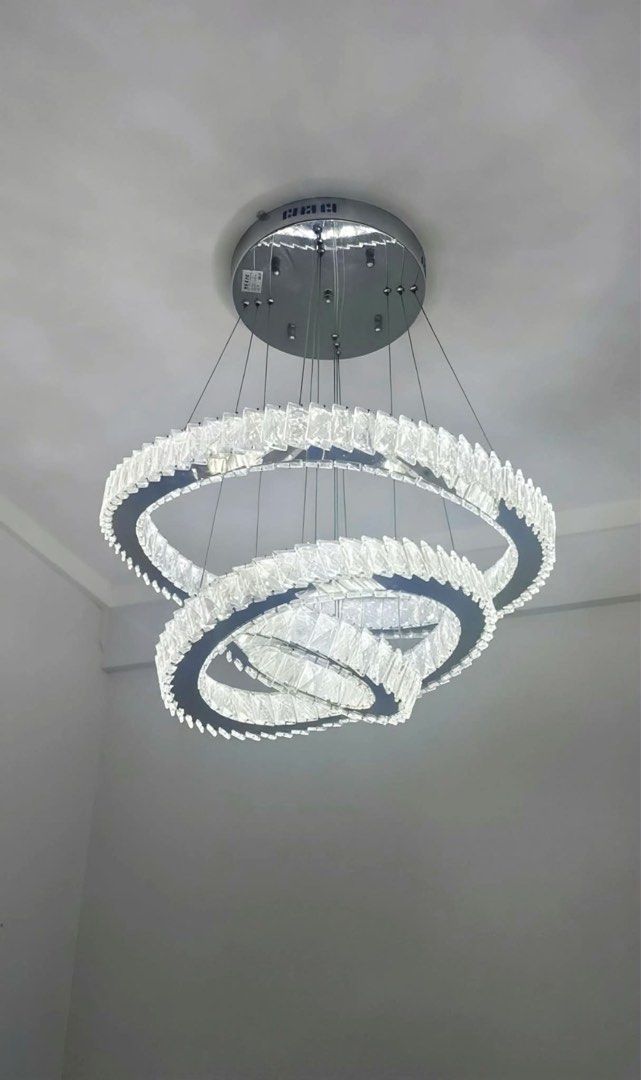 Modern Crystal Ring Chandelier Light Fixture (Category: Lighting) located in Manila. Submitted by d_carthub (Listing ID 1461590410, Image 2). Description: - Beautiful modern chandelier - Features three intertwined crystal rings - Silver-toned metal base - Emits bright, clear light, warm light - Ideal for living rooms, dining areas, or entryways - Adds a touch of sparkle - Wiring and mounting hardware included - 3 way light color.