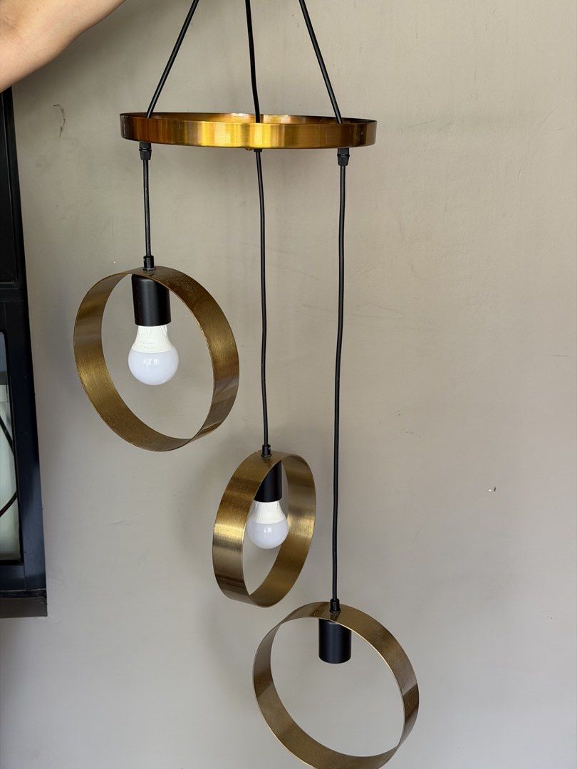 Modern Gold Ring Pendant Light Fixture (Category: Lighting) located in Manila. Submitted by alexcassan66173 (Listing ID 1461620812, Image 2). Description: - Modern hanging pendant light - Features three gold rings, each holding a bulb - Suspended by black cords - Topped with a gold circular plate - Adds a contemporary touch to any space - Ideal for dining areas or living rooms.
