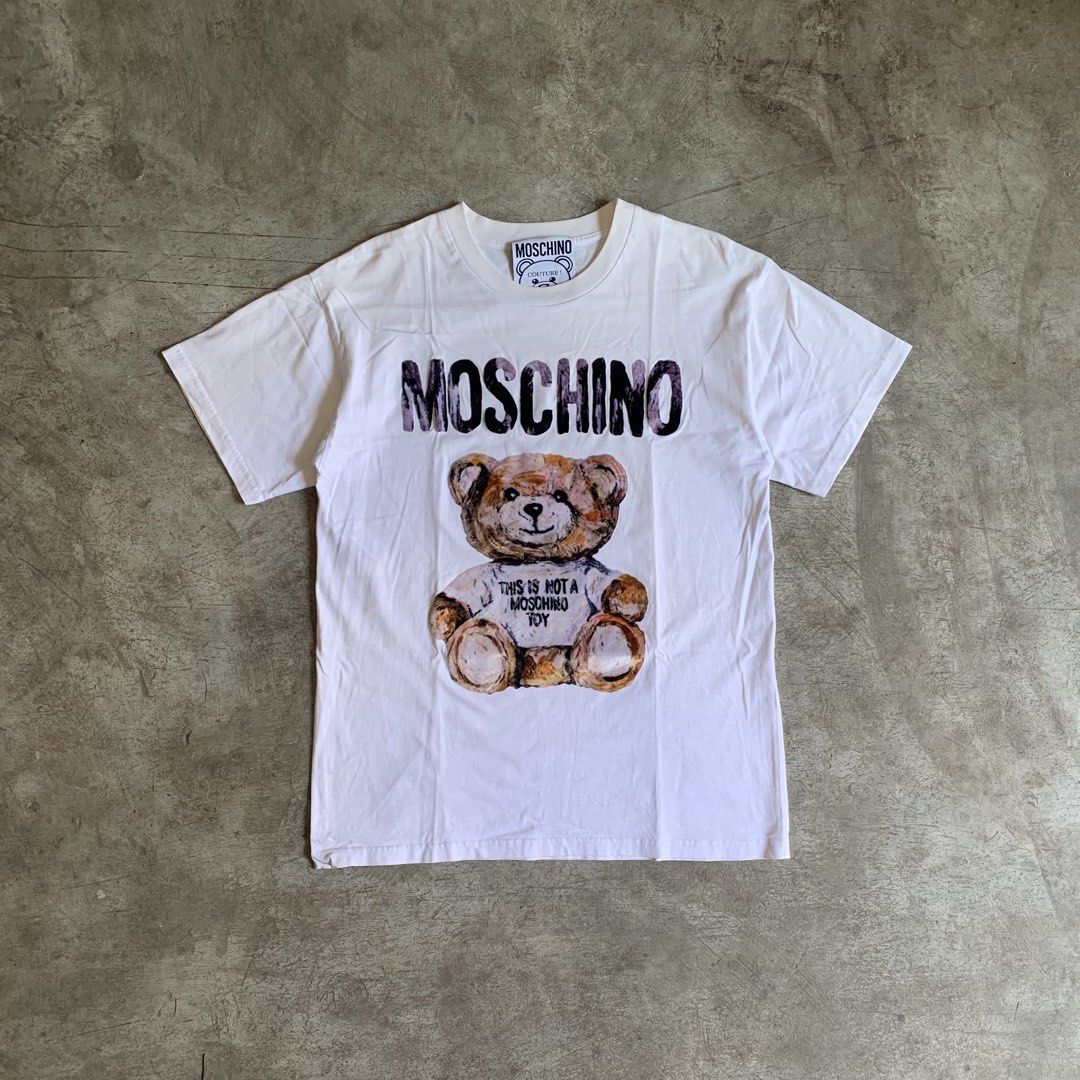 MOSCHINO Teddy Bear T-Shirt White (Category: Activewear) located in Manila. Submitted by emplysthrift. (Listing ID 1461729169, Image 1). Description: Moschino Couture Teddy Bear Graphic Tshirt Width "20.5 Length "27 Excellent Condition Colorrate: 9.3/10 Flaws: none Unli vouchers/vc for safe transactions 📲 Location: Laspinas City, Metro Manila, Brngy Talon Uno. 📍 DM IF INTERESTED📥 - Iconic Moschino Teddy Bear graphic - "This is not a Moschino T