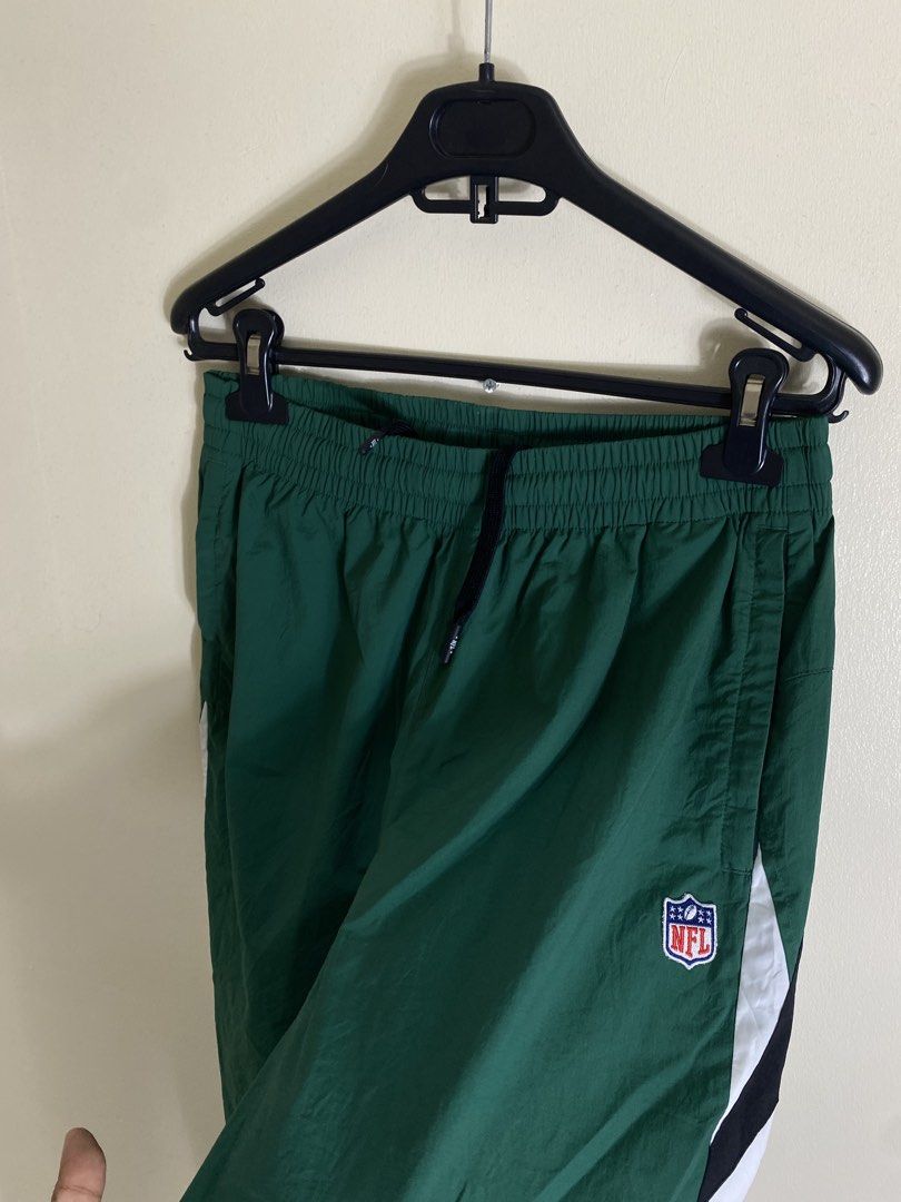 NFL Team Apparel Green Track Pants (Category: Joggers) located in Cebu City. Submitted by theloose.thread (Listing ID 1461781091, Image 2). Description: - Green NFL track pants - White and black side stripes - Elastic waistband with drawstring - NFL logo on right leg - Ideal for casual wear or sports - Made from a polyester and polyurethane blend.