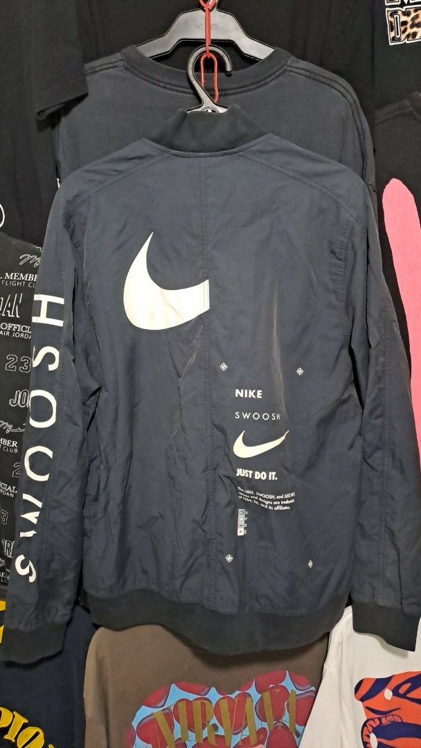 Nike Bomber Jacket Black Swoosh Logo (Category: Coats, Jackets and Outerwear) located in San Fernando. Submitted by anal.cris (Listing ID 1461579240, Image 2). Description: - Classic Nike bomber jacket style - Prominent Nike Swoosh logo on the front - Large, eye-catching Swoosh graphic on the back - Features text details on both front and back - Comfortable ribbed collar, cuffs, and hem - Easy full zip closure - Needs washing.
