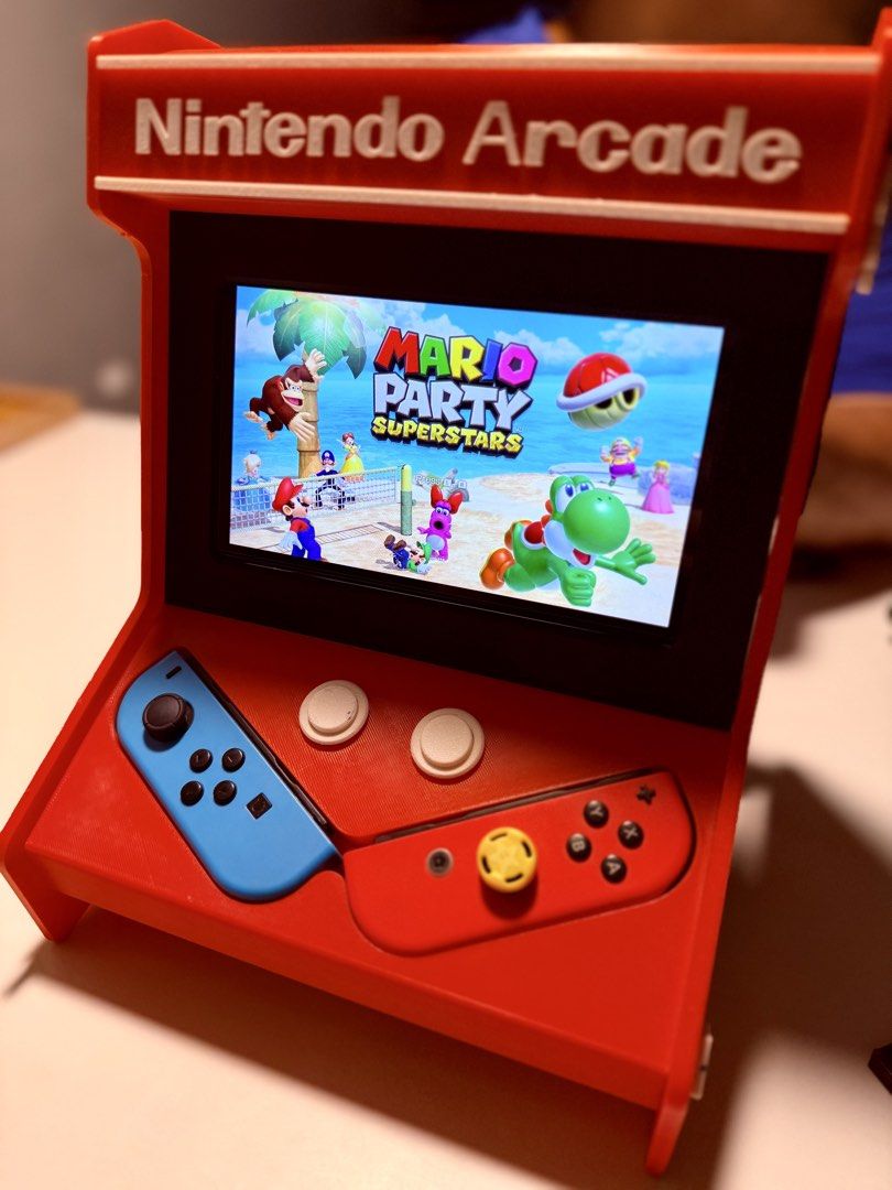Nintendo Arcade Mini Machine with Mario Party Superstars (Category: Nintendo) located in Manila. Submitted by irish_c (Listing ID 1461685516, Image 2). Description: - Mini Nintendo Arcade Machine - Features Mario Party Superstars on screen - Comes with blue and red Joy-Con style controllers - Includes a pull-out tray at the bottom - Decorated with Mario and other Nintendo characters - Approximately 29cm tall.