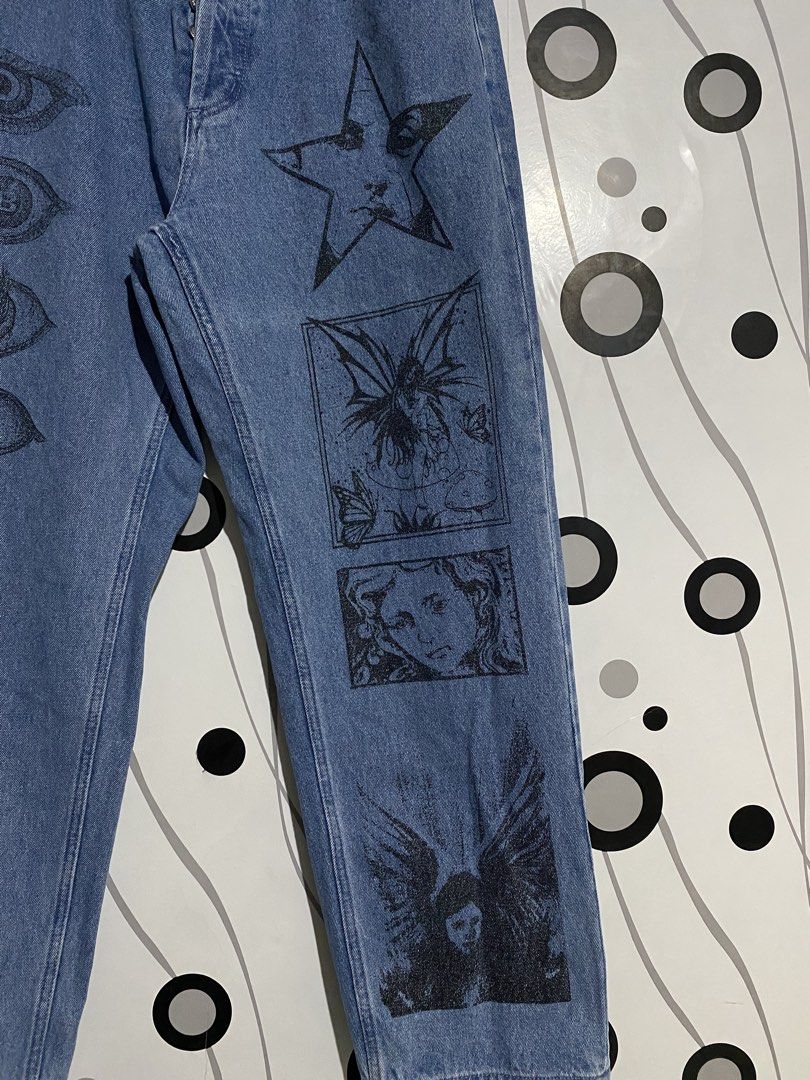 OBEY Hard Work Dreams denim jeans (Category: Jeans) located in Cebu City. Submitted by patspickph (Listing ID 1461614652, Image 2). Description: The image shows a pair of light indigo OBEY Hard Work Dreams denim jeans decorated with striking graphic prints of a vertical row of eyes and celestial artwork. Dimensions is W32-34 and length is 39inches. No issue Excellent Condition👍👌.
