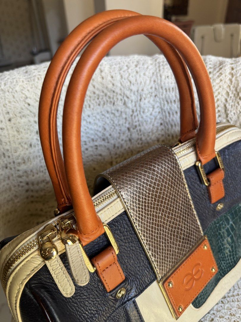 Patchwork Handbag (Category: Luxury Bags & Wallets) located in Bacolod City. Submitted by vintage_vogue6100 (Listing ID 1461667628, Image 3). Description: Style & Shape: A structured, barrel-shaped satchel bag (similar to a Boston bag) with dual rolled top handles and a main zipper closure. Colors & Patterns: A multi-colored blocked design combining navy blue, cream, orange, and emerald green paneling. Textures: A mix of pebbled leather, smooth c