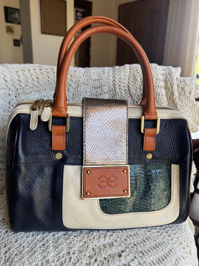 Patchwork Handbag (Category: Luxury Bags & Wallets) located in Bacolod City. Submitted by vintage_vogue6100 (Listing ID 1461667628, Image 1). Description: Style & Shape: A structured, barrel-shaped satchel bag (similar to a Boston bag) with dual rolled top handles and a main zipper closure. Colors & Patterns: A multi-colored blocked design combining navy blue, cream, orange, and emerald green paneling. Textures: A mix of pebbled leather, smooth c