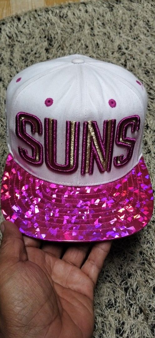 Phoenix Suns unisex NBA Snapback Cap White Pink Sparkle (Category: Caps & Hats) located in Paranaque City. Submitted by michael-08 (Listing ID 1461619151, Image 1). Description: - White snapback cap - Pink sparkle brim - 'SUNS' embroidered in gold and pink on the front - NBA logo on the side - Phoenix Suns logo on the back - Adjustable strap for a custom fit - Perfect for Phoenix Suns fans! UNISEX PO AUTHENTIC.WALA PO ISSUE GOOD CONDITION LIKE A 
