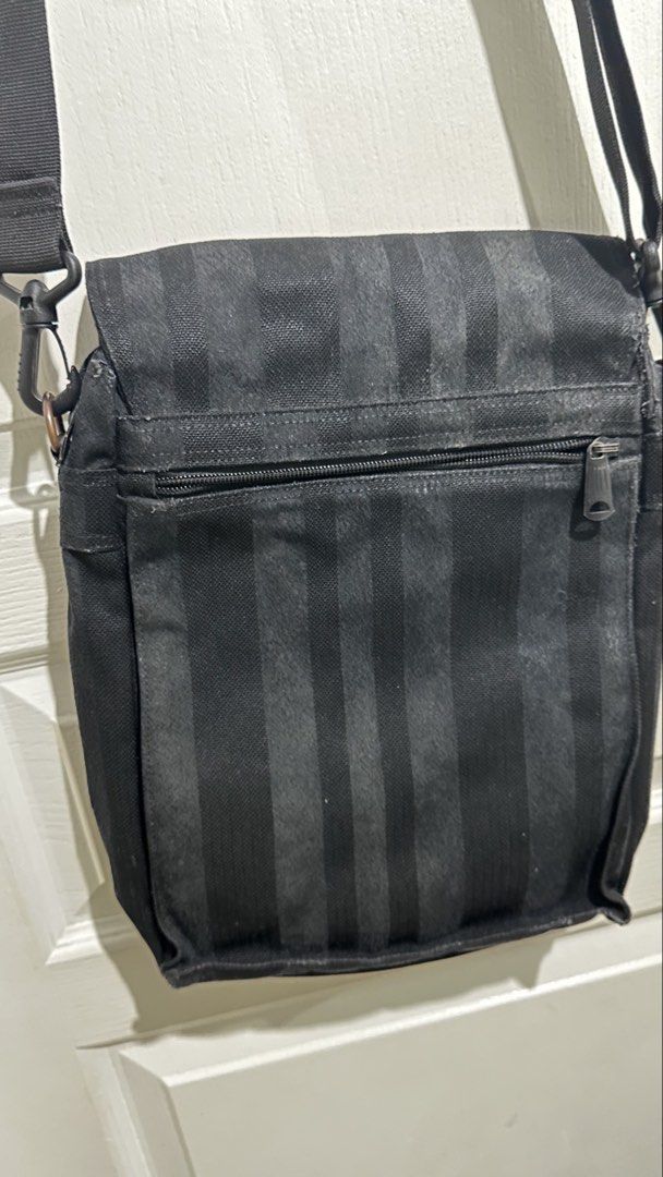 Porter Yoshida & Co. Black Striped Messenger Bag (Category: Sling Bags) located in Mandaluyong City. Submitted by TheWeekendProject (Listing ID 1461713781, Image 2). Description: - Brand: Porter Yoshida & Co. - Color: Black - Design: Subtle vertical stripe pattern - Compartments: Main compartment with internal pockets, zippered front pocket - Strap: Adjustable shoulder strap with padding (note: this is a replacement strap) - Use: Ideal for everyd