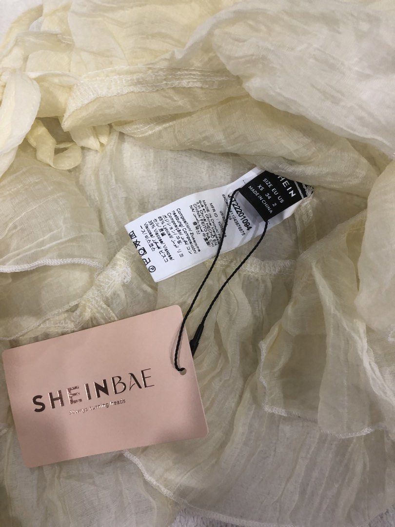 SHEINBAE Sheer Ruffle Long Sleeve Top (Category: Longsleeves) located in Manila. Submitted by janmichael26601 (Listing ID 1461619009, Image 3). Description: - Brand new with tags attached - Cream sheer fabric - Long ruffled sleeves - Tie front closure - Ruffled hemline - Lightweight and flowy material - Ideal for layering or as a standalone statement piece.
