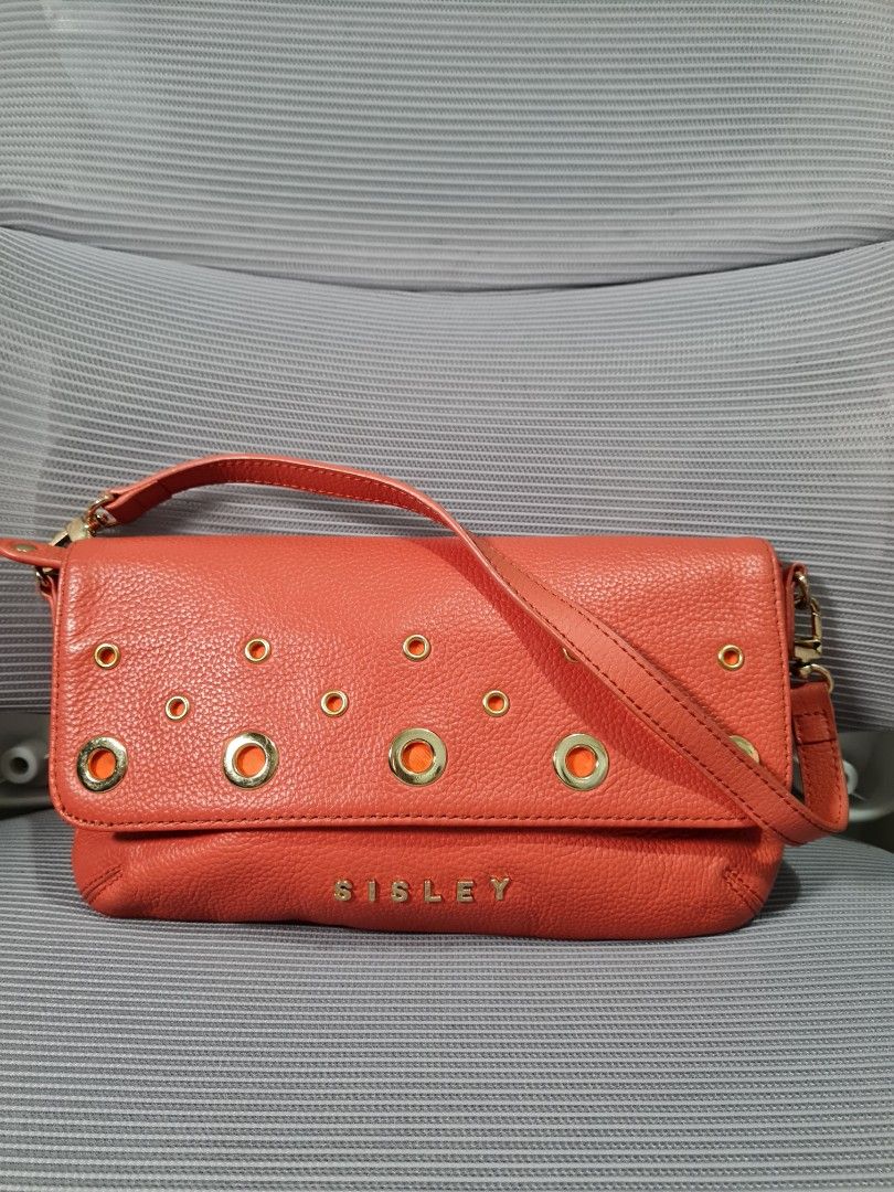 Sisley kili bag (Category: Shoulder Bags) located in Quezon City. Submitted by missmaui (Listing ID 1461780322, Image 1). Description: This is a Sisley leather shoulder/crossbody flap bag with gold eyelet details. * Brand: Sisley * Color: Coral / Salmon Pink * Material: Pebbled leather * Key Features: Gold-tone hardware/grommets scattered across the front flap, a main flap enclosure, and a matching leather strap..