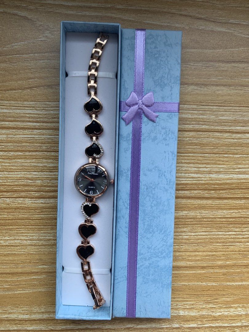 Sunflower Quartz Watch with Heart Bracelet (Category: Women's Watches) located in Caloocan City. Submitted by lb.clothing (Listing ID 1461629293, Image 1). Description: Cute watch with a rose gold chain and black heart charms. The watch face is black with rose gold hands and numbers. It says 'Sunflower' and 'Quartz' on the face. Comes in a light blue gift box with a purple ribbon. Great for gifting or treating yourself..