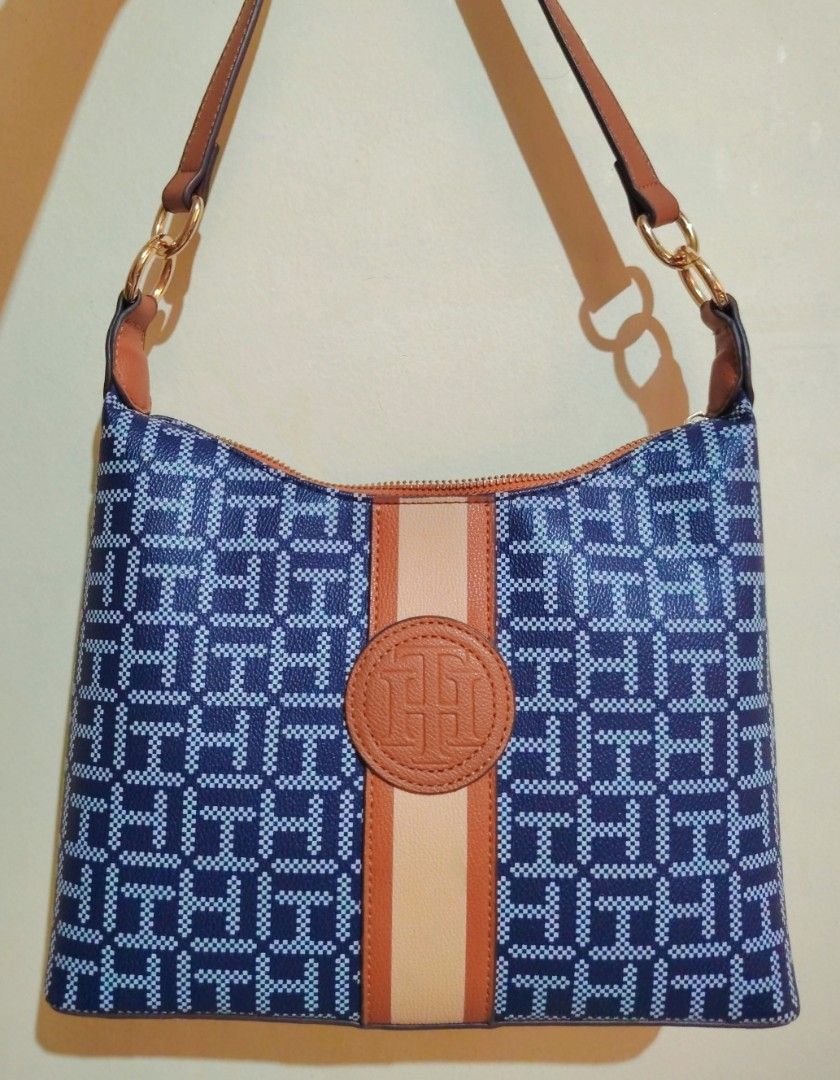 Tommy Hilfiger Monogram Shoulder Bag (Category: Shoulder Bags) located in Manila. Submitted by iamsaeemieese (Listing ID 1461667541, Image 1). Description: - Classic Tommy Hilfiger monogram pattern - Tan accents for a stylish touch - Circular logo detail - Adjustable strap with gold hardware - Zip closure for security - Ideal for everyday wear.