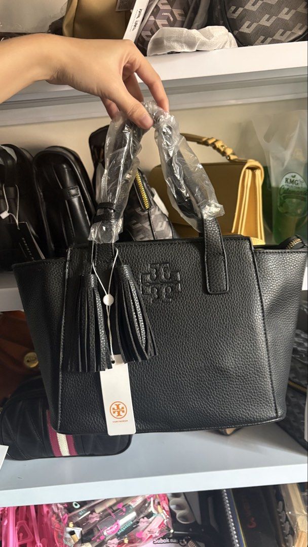 Tory Burch (tg) (Category: Tote Bags) located in Manila. Submitted by kathrinafu07589 (Listing ID 1461655731, Image 1). Description: - Authentic Tory Burch black pebbled leather tote bag - Features signature Tory Burch logo embossed on the front - Stylish decorative tassels - Secure top zip closure - Handles still protected with original plastic wrap - Comes with original tags attached.