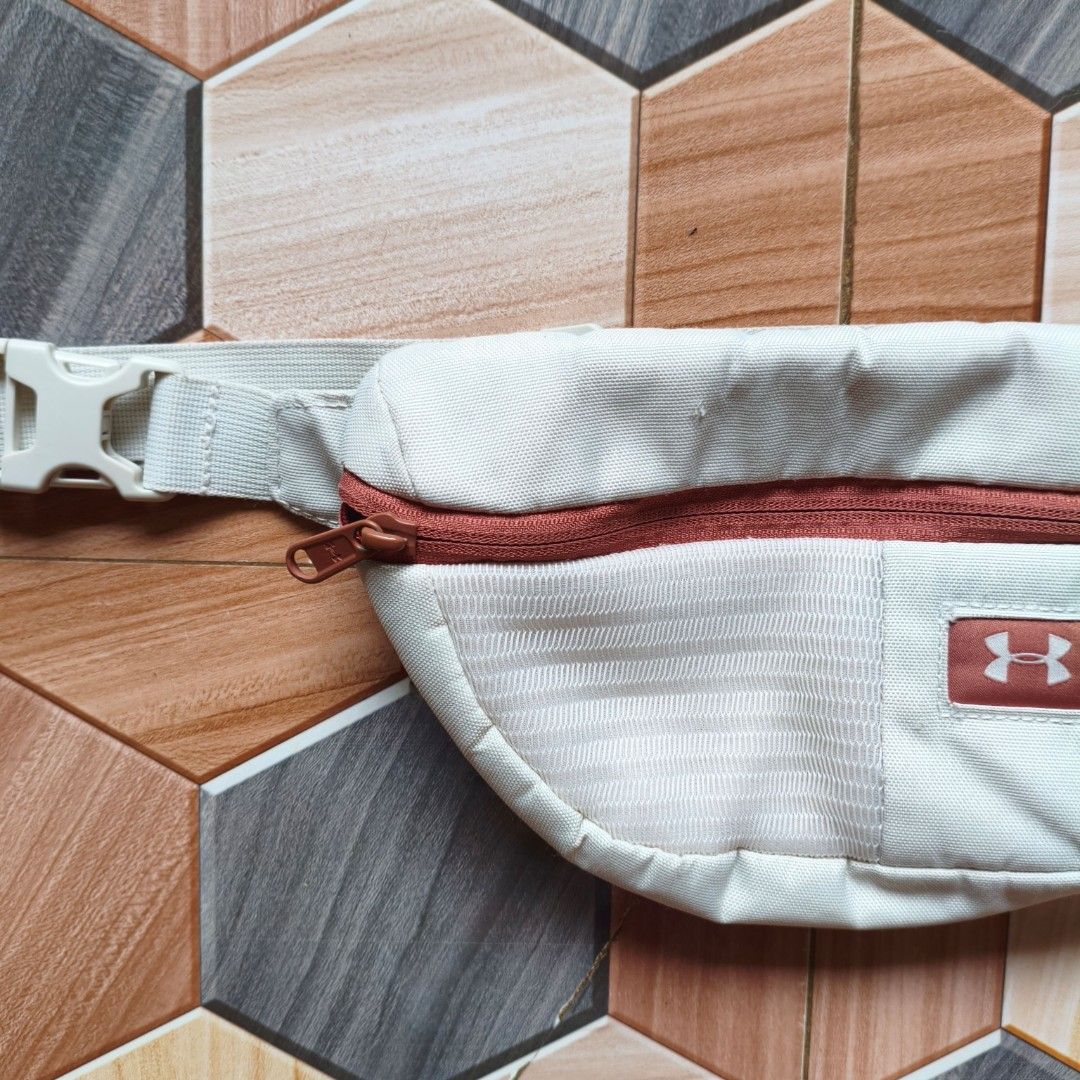 Under Armour White Fanny Pack Bum Bag (Category: Belt bags, Clutches and Pouches) located in Manila. Submitted by caps08 (Listing ID 1461594637, Image 3). Description: - White Under Armour fanny pack - Reddish-brown zipper and logo patch - Adjustable strap with buckle closure - Ideal for keeping essentials handy - Perfect for workouts or casual outings - Shows minimal signs of wear.