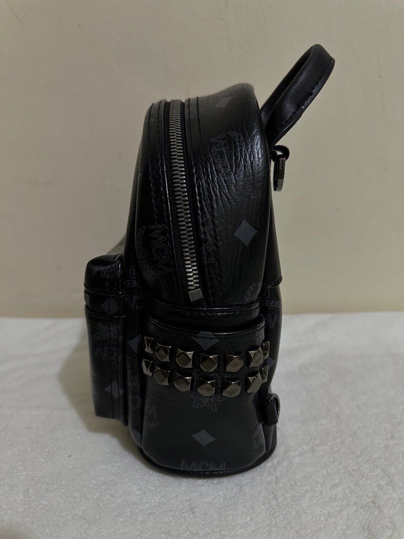 MCM Visetos Side Stud X-Mini Stark Bebe Boo Backpack Black (Category: Backpacks) located in Las Pinas. Submitted by bagsbyshai (Listing ID 1461700594, Image 3). Description: This is the authentic MCM Visetos Side Stud X-Mini Stark Bebe Boo Backpack in Black. This backpack is crafted of MCM monogram print coated canvas in black. It features a studded patch pocket on either side, polished ruthenium hardware, a rolled leather handle, an adjustable s