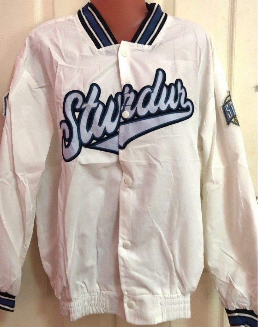 White Varsity Jacket with "Sturdur" Logo (Category: Coats, Jackets and Outerwear) located in Antipolo. Submitted by strawberricae (Listing ID 1461748615, Image 1). Description: - Classic white varsity jacket - Blue and black striped collar and cuffs - Large embroidered 'Sturdur' logo on the front - Smaller patch detail on the sleeve - Easy button-up closure - Ideal for everyday casual wear.
