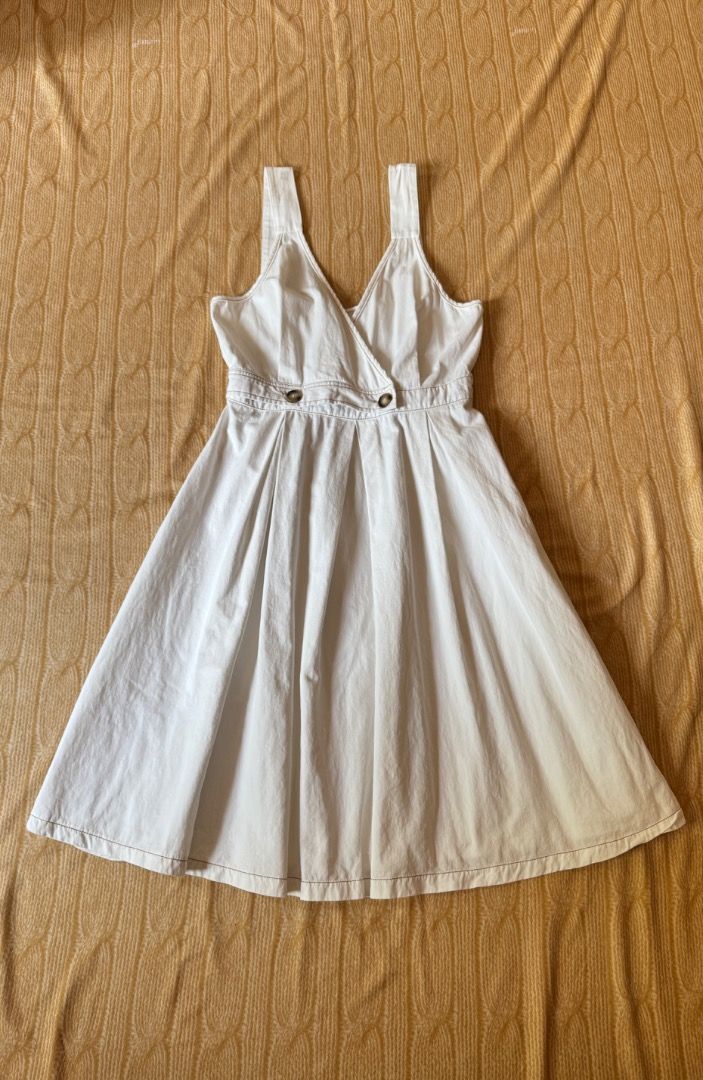 White Wrap Dress with Button Detail (Category: Dresses) located in Calasiao. Submitted by clothesbykim (Listing ID 1461701002, Image 1). Description: - White wrap dress - Size M - Brown contrast stitching - Two large brown buttons at the waist - Denim or sturdy cotton material - Ideal for casual outings.