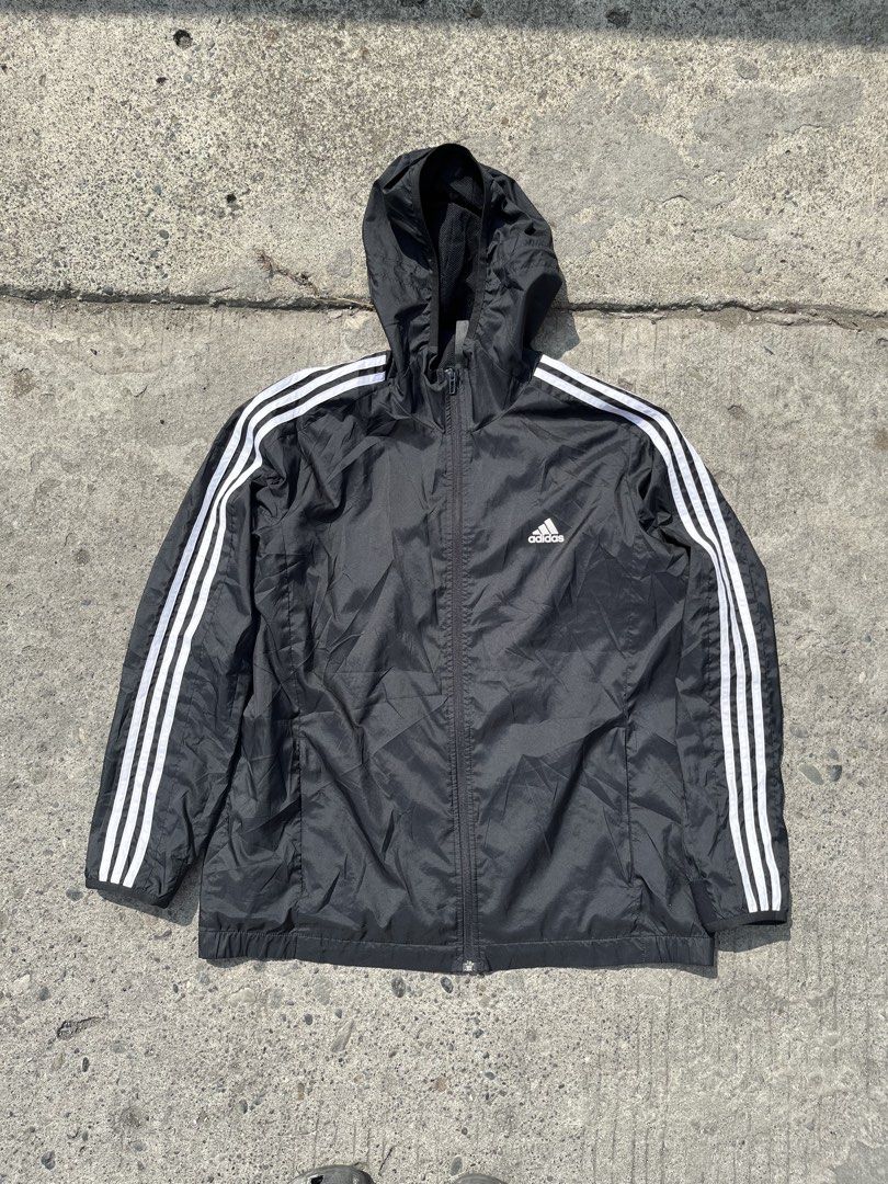 Adidas Black Windbreaker Jacket with White Stripes (Category: Coats, Jackets and Outerwear) located in Davao. Submitted by notoriousthrift (Listing ID 1461857189, Image 1). Description: - Classic black Adidas windbreaker jacket - Iconic three white stripes on sleeves - Features a hood - Zippered pockets for secure storage - Made in Indonesia - Size: 2XL -Dimes 23x29 - Ideal for casual wear or sports activities.