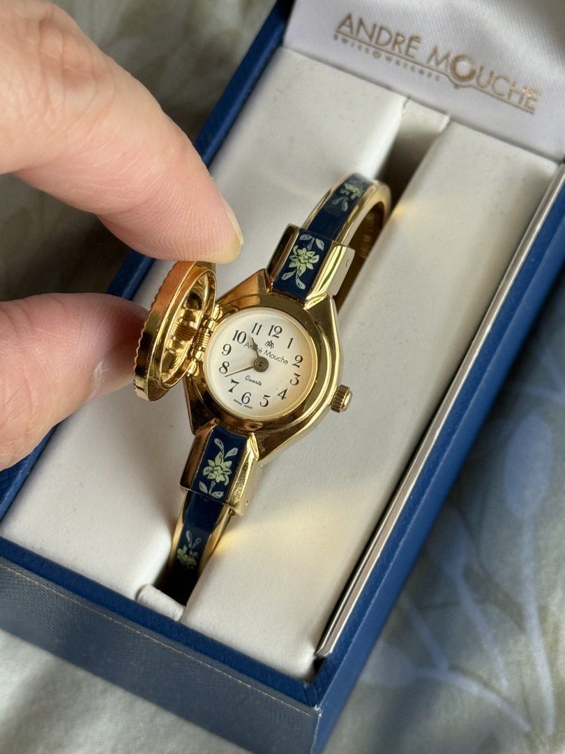 Andre Mouche Swiss Made Edelweiss Bangle Watch (Category: Women's Watches) located in Manila. Submitted by beaalipon (Listing ID 1461818496, Image 3). Description: - Authentic Andre Mouche Swiss Made watch - Elegant gold tone bangle - Dark blue enamel band with delicate edelweiss floral design - Classic white watch face with clear black numbers - Comes with original box - Includes international guarantee certificate - 14-16cm Location: BGC.