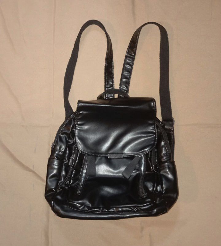 Black Faux Leather Drawstring Backpack with Zippers Preloved (Category: Backpacks) located in Manila. Submitted by hi.yunichi (Listing ID 1462009408, Image 1). Description: - Stylish black faux leather backpack - Secure drawstring closure hidden under a flap - Two convenient zippered pockets on the front - Adjustable straps for a comfortable fit - Ample interior space for all your essentials - Ideal for everyday use or your next travel adventure.