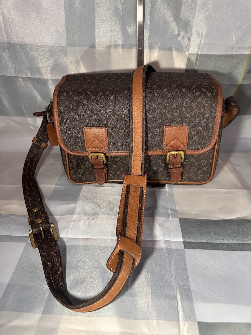 Brown Monogram Crossbody Bag with Leather Trim (Category: Cross-body Bags) located in Cavite. Submitted by bags_unltd143 (Listing ID 1461839389, Image 2). Description: Brown crossbody bag with a repeating monogram pattern. Features tan leather trim and buckle details on the front flap. Adjustable shoulder strap. Zipper closure on top. Front pocket also has a snap closure. Great for everyday use..