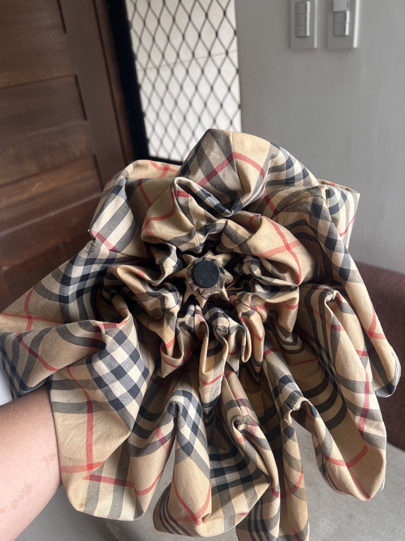 Burberry Check Folding Umbrella (Category: Umbrellas) located in San Juan, La Union. Submitted by jeggystyle (Listing ID 1461965670, Image 3). Description: - Classic Burberry check design - Folding umbrella for portability - Smooth opening and closing mechanism - Features a stylish wood-look handle - Secure button closure on the strap - Perfect for rainy weather - Shows minor signs of wear, but fully functional.