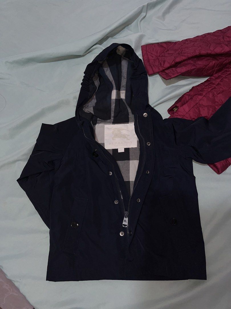 Burberry Children's Navy Blue Hooded Jacket (Category: Babies & Kids Fashion) located in Tabuk. Submitted by collectors_thrift_shop (Listing ID 1461955813, Image 1). Description: - Burberry Children's Jacket - Color: Navy Blue - Size: 24 Months - Iconic Burberry Check Lining - Hooded Design - Zip and Button Closure - Perfect for keeping your child warm and stylish.