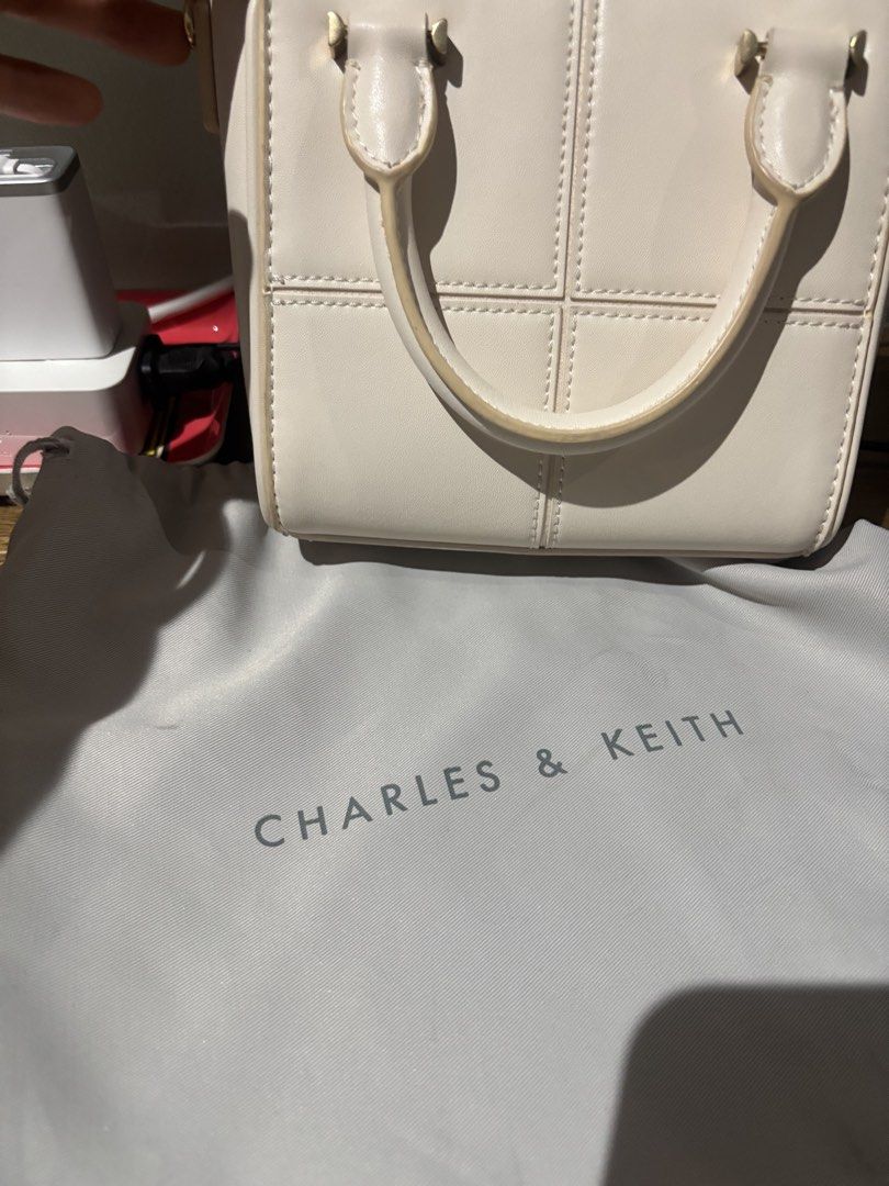 Charles & Keith White Top Handle Bag (Category: Luxury Bags & Wallets) located in Paranaque City. Submitted by corinne_see (Listing ID 1461921716, Image 2). Description: - Brand: Charles & Keith - Color: White - Style: Top handle bag - Design: Structured with stitched panel details - Straps: Top handle and detachable shoulder strap - Hardware: Gold accents - Includes: Original dust bag - Versatile: Suitable for daily use or special occasions.