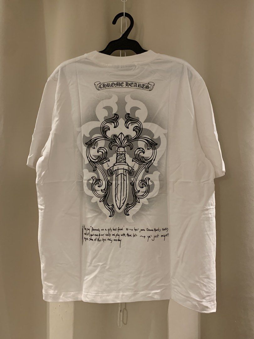 Chrome Hearts White T-Shirt (Category: Tshirts & Polo Shirts ) located in Manila. Submitted by vintaurafindsco. (Listing ID 1461829088, Image 1). Description: - Authentic White Chrome Hearts T-shirt - Features iconic dagger and scroll design on the back - Subtle Chrome Hearts logo on the front chest - Brand new with tag still attached - A must-have for any Chrome Hearts enthusiast or collector.