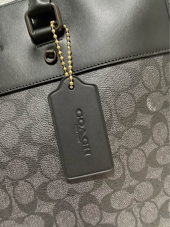 Coach mens bag Gotham Portfolio (Category: Luxury Bags & Wallets) located in Caloocan City. Submitted by benbo18 (Listing ID 1461802674, Image 3). Description: Brand: COACH New York Style: Structured top-handle work/portfolio bag Color: Black with dark charcoal/black Coach Signature pattern Material appearance: Smooth black leather or leather-like upper section with Signature coated canvas on the lower portion. Coach confirms that its Signature c