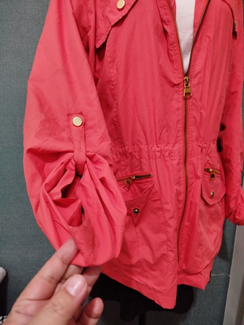 Coral Hooded Drawstring Jacket with Gold Zippers (Category: Coats, Jackets and Outerwear) located in Quezon City. Submitted by plus4lessshop (Listing ID 1461837696, Image 2). Description: - Coral colored jacket - Attached hood - Drawstring waist for adjustable fit - Gold zippers on pockets and front closure - Sleeves can be rolled up and secured with button tabs - Lightweight material, ideal for layering - Perfect for casual outings.