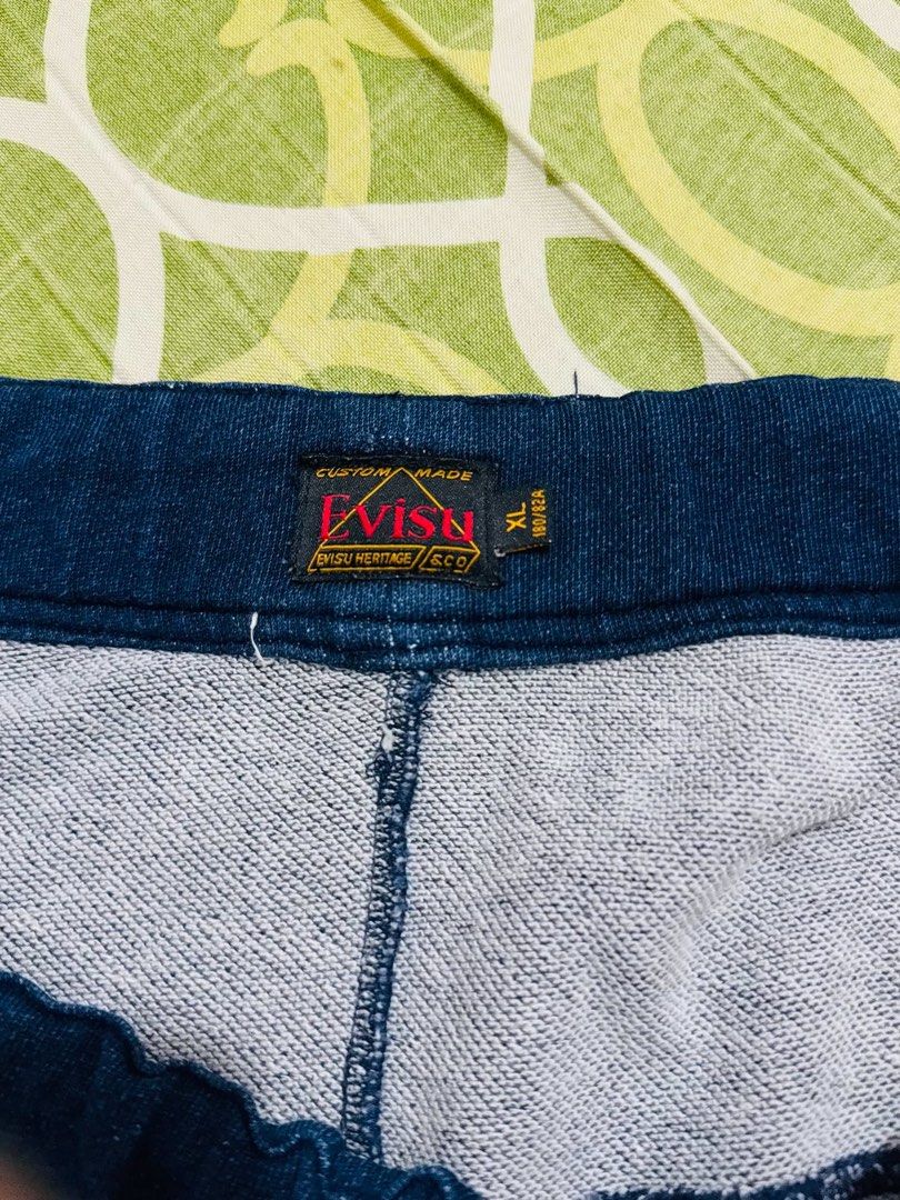 EVISU Custom Made Denim Shorts XL (Category: Shorts) located in Guagua. Submitted by eloisa.dpthrifts11 (Listing ID 1461995761, Image 3). Description: -Waist: 38-42” -Length: 20” - Brand: EVISU - Type: Custom Made Denim Shorts - Size: XL - Features: Iconic EVISU logo on back - Detail: Two red stripes on back pockets - Condition: Small mark on front (refer to last photo) - Style: Great for casual wear -issue small pinhole .