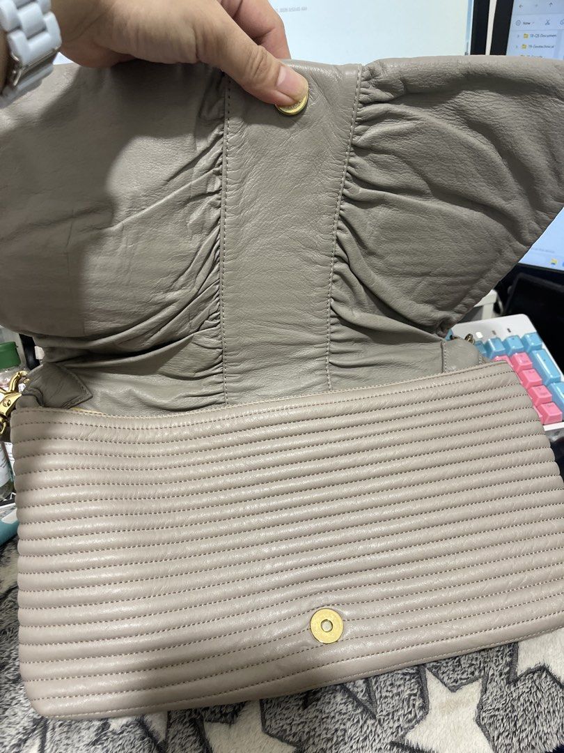 Grey Leather Ruched Clutch Bag with Gold Hardware (Category: Clutches) located in Cainta. Submitted by theashop_ph (Listing ID 1461842892, Image 2). Description: - Elegant grey leather clutch - Stylish ruched detailing - Gathered strap for a unique look - Gold hardware accents - Secure magnetic snap closure - Convenient zippered interior pocket - Ideal for evening events or as a statement accessory.