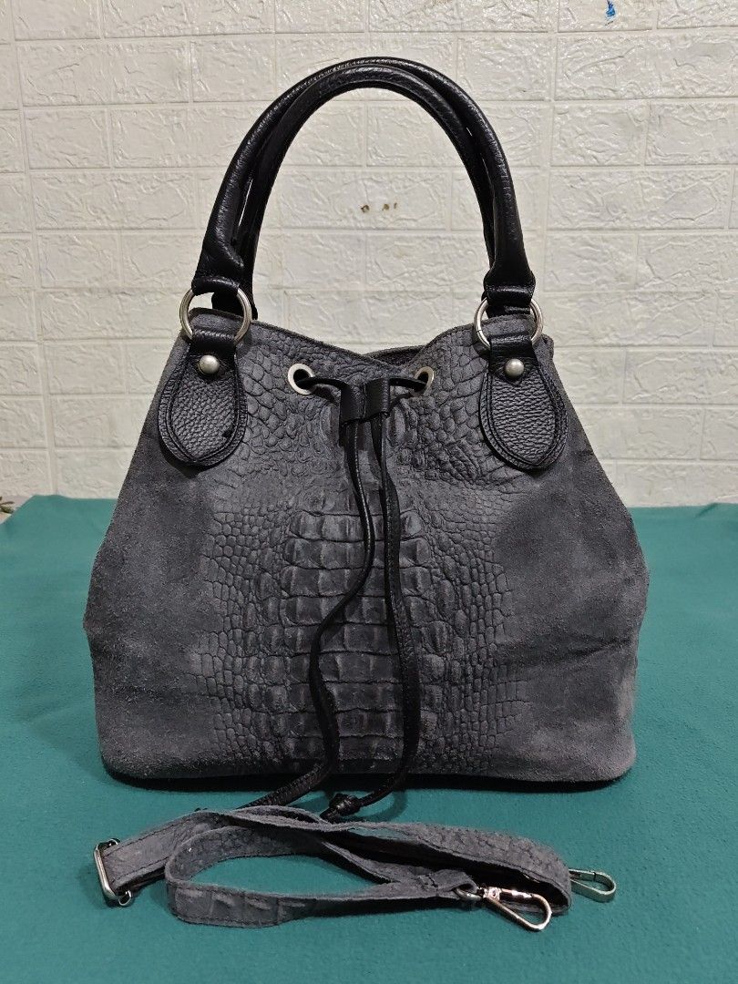 Grey Suede Crocodile Embossed Bucket Bag (Category: Cross-body Bags) located in Gamu. Submitted by charliecatvintagebags (Listing ID 1461818074, Image 2). Description: GENUINE LEATHER WALANG ISSUE - Grey suede bucket bag - Black leather trim - Crocodile embossed pattern on front - Drawstring closure - Detachable shoulder strap - Silver hardware - Roomy interior.