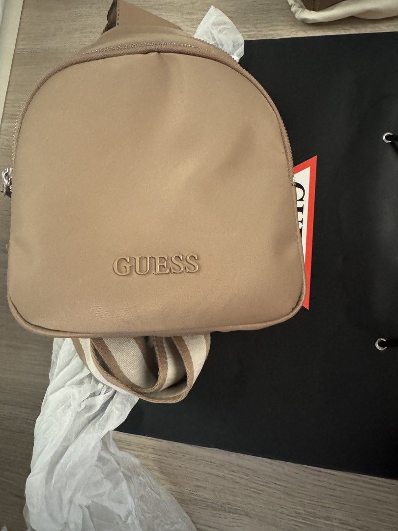 Guess Sling Bag (Category: Cross-body Bags) located in Paranaque City. Submitted by cleverturtle.391c7c (Listing ID 1461807452, Image 2). Description: - Tan colored Guess sling bag - Features embossed Guess logo on the front - Comes with a black Guess shopping bag - Ideal for everyday use.