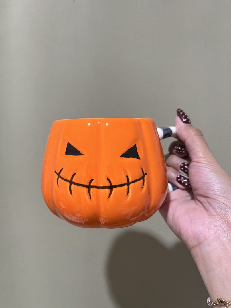 Halloween Pumpkin Ceramic Mug with Striped Handle (Category: Coffee & Tea Tableware) located in Manila. Submitted by vaughnscloset (Listing ID 1461947809, Image 1). Description: - Orange pumpkin-shaped mug - Features a carved jack-o'-lantern face - Black and white striped handle - Ideal for morning coffee or tea - Perfect addition to your Halloween kitchenware - Pinholes on the handle - small paint chip (orange).