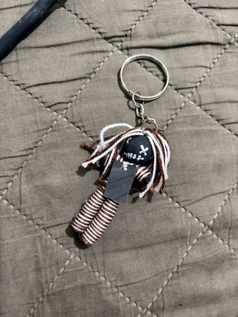 Handmade Voodoo Doll Keychain with Black Tag (Category: Plushies & Soft Toys) located in Manila. Submitted by finderskeepersmnl_092026 (Listing ID 1461979604, Image 1). Description: - Adorable handmade doll keychain - Unique black head with white stitched face - Brown and white striped thread body - Includes a small black tag - Ideal accessory for bags or keys.