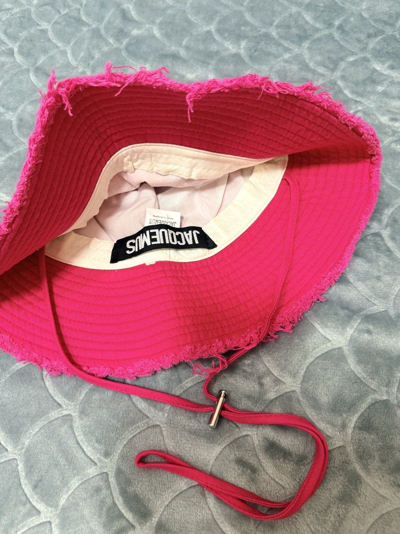 Jacquemus Pink Frayed Bucket Hat (Category: Hats & Beanies) located in Tarlac. Submitted by kylienclrzbl (Listing ID 1461917883, Image 2). Description: - Bright pink Jacquemus bucket hat - Features frayed edges for a distressed look - Adjustable drawstring with silver toggle - Perfect for sunny days - Minor signs of wear on the brim.