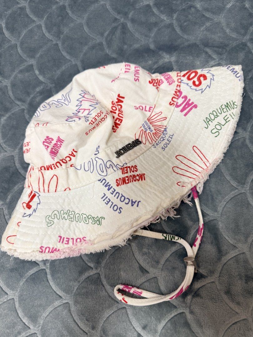 Jacquemus Soleil Bucket Hat White All Over Print (Category: Hats & Beanies) located in Tarlac. Submitted by kylienclrzbl (Listing ID 1461918002, Image 1). Description: - White bucket hat with all-over Jacquemus Soleil print - Features a frayed brim - Includes a drawstring for adjustable fit - Fun graphics all over - Ideal for sunny days and outdoor activities.